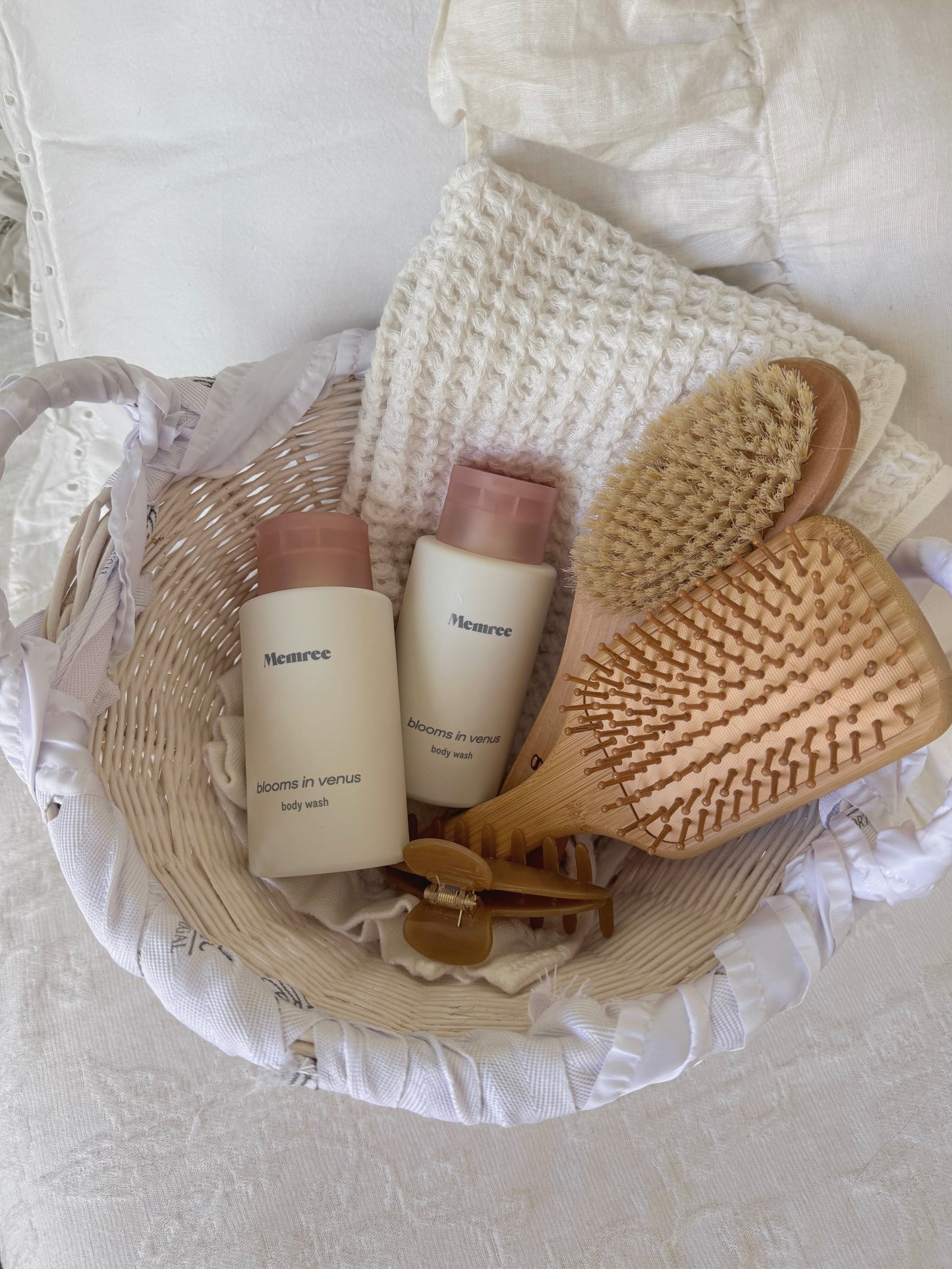 Two Memree blooms in venus bodywashes neatly arranged in a woven basket.