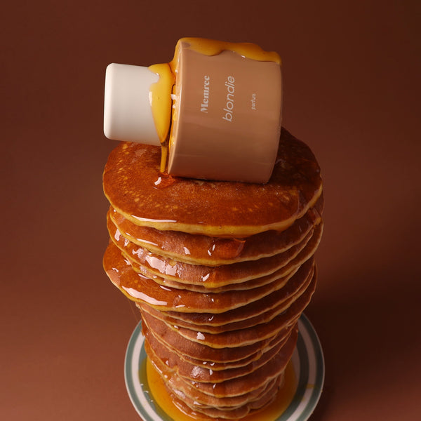Blondie parfum bottle balanced on top of a tall stack of syrup glazed pancakes